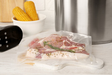 Vacuum packing with meat on white wooden table. Sous vide cooking