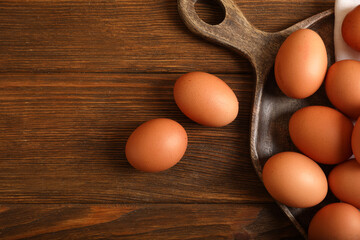 Raw brown chicken eggs on wooden table, flat lay. Space for text