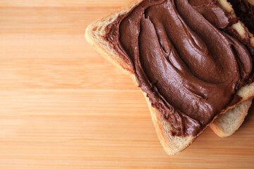 Tasty toast with chocolate paste on wooden table, top view. Space for text