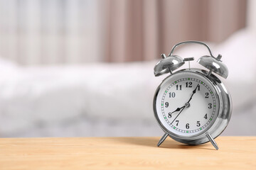 Silver alarm clock on wooden table indoors. Space for text