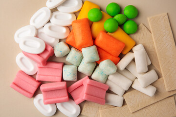 Many different chewing gums on beige background, flat lay