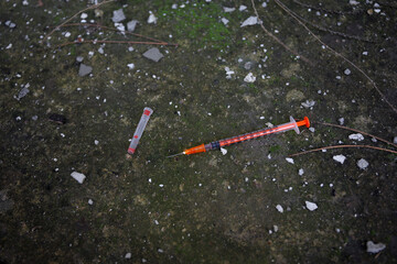 Empty disposable syringe with needle on street