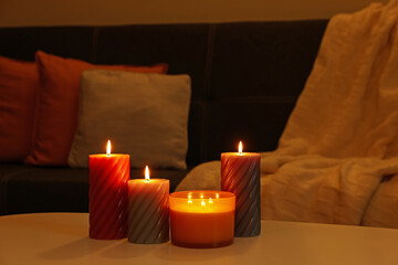 Burning candles on white table indoors. Cosy atmosphere