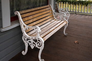 Wooden bench with a decorative ornate metal legs and armrests. Garden white bench with a...