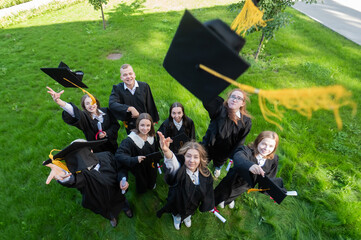 Classmates in graduation gowns throw their caps. View from above. 