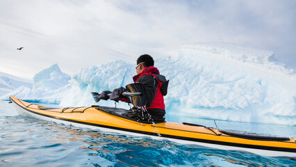A man is paddling a sea kayak in Wilhelmina Bay, Antarctic Peninsula, Antarctica.