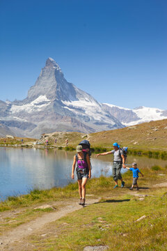 Family hiking on lakeshore in Swiss Alps with Matterhorn in background, Zermatt, Valais, Switzerland