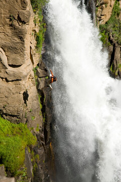 Climber rappells next to waterfall.