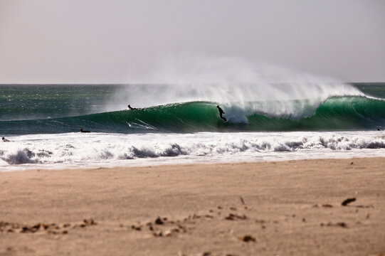 A surfer leans into a bottom turn while surfing in Oxnard, California during Santa Anna conditions.