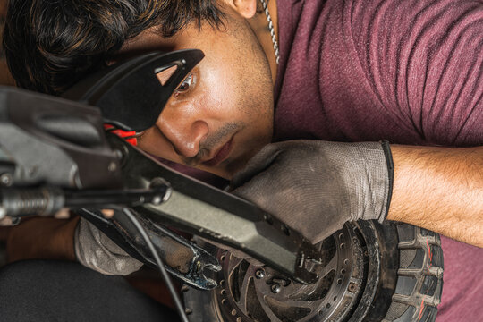 Close up of a latin mechanic checking  the wiring of a  scooter