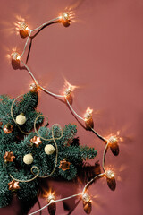 Christmas decorations, baubles, cones and ribbons on natural fir twig. Xmas background on orange brown paper with electric light garland. Flat lay, top view with copy-space, place for text overhead.