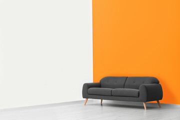 Stylish room with cosy sofa near orange wall, space for text. Interior design