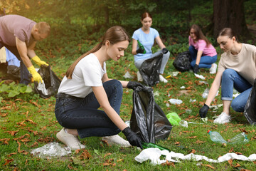 Group of people with plastic bags collecting garbage in park