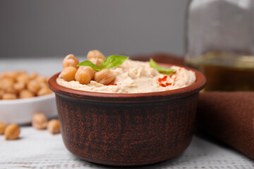 Delicious hummus with chickpeas and paprika served on white wooden table, closeup