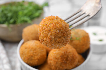 Taking delicious fried tofu ball with fork from bowl, closeup