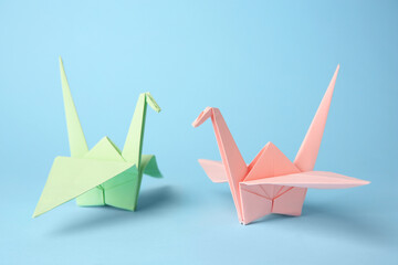 Origami art. Colorful handmade paper cranes on light blue background