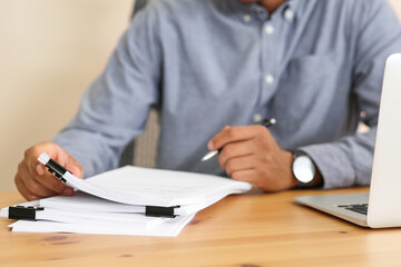 Man working with documents at wooden table in office, closeup