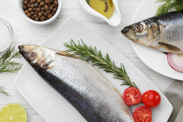 Delicious salted herrings and ingredients on white wooden table, flat lay