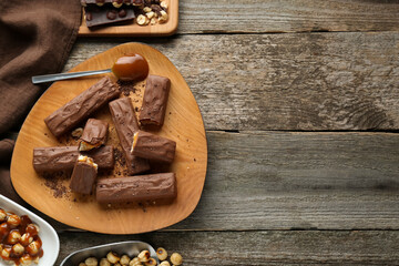 Tasty chocolate bars with caramel and nuts on wooden table, flat lay. Space for text