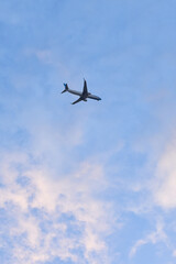 Fototapeta na wymiar silueta de avion comercial volando al atardecer con nubes coloridas