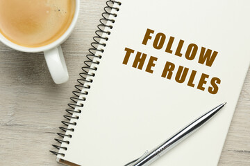 Notebook with phrase Follow The Rules, pen and cup of coffee on wooden table, flat lay