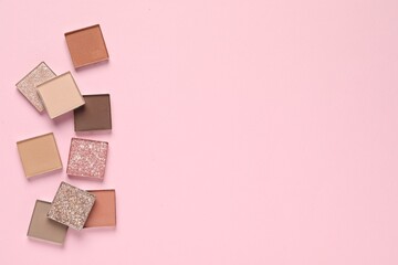 Different beautiful eye shadows on pink background, flat lay. Space for text