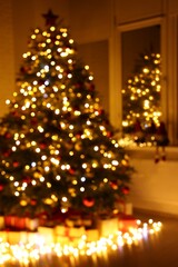 Beautiful Christmas tree, gifts and festive lights near window in room, blurred view