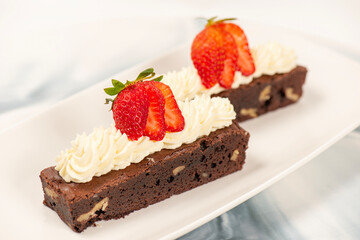 Deliciously rich cake brownie slice with Chantilly cream and fresh strawberry.