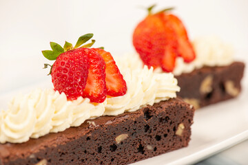 Deliciously rich cake brownie slice with Chantilly cream and fresh strawberry.