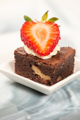 Deliciously rich cake brownie slice with Chantilly cream and fresh strawberry.