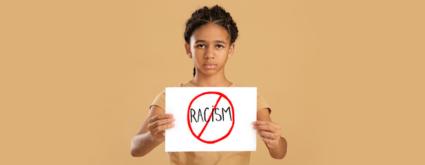 African-American girl with poster on beige background. Stop racism