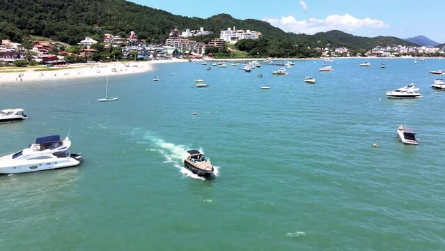 Low flight drone aerial scene flying over speedboats yachts and luxury boats with pier in paradisiaca beach in Jurere internacional florianopolis santa catarina