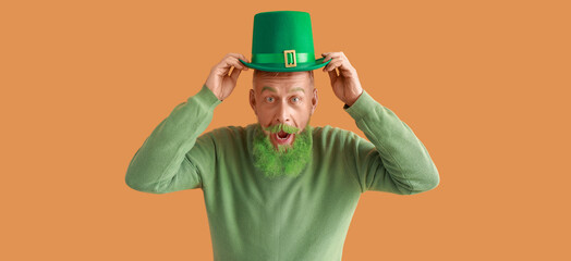 Funny surprised mature man with green beard on orange background. St. Patrick's Day celebration