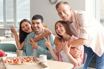 Group of friends showing victory gesture in kitchen