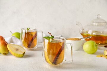 Glass cup of fruit tea with pear, mint and cinnamon on light background, closeup
