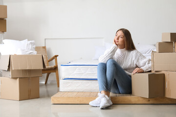Dreaming young woman with cardboard boxes in bedroom on moving day