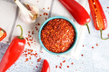 Bowl with chipotle chili flakes on light background