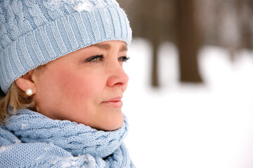 Close up portrait of attractive mature woman outdoors in winter wearing knit scarf and tuque.