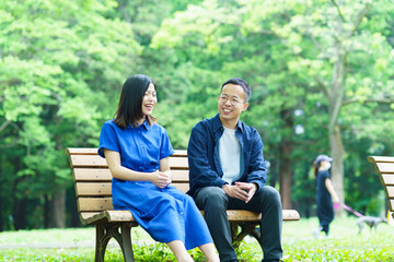 公園のベンチで談笑する若いカップル 