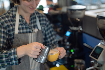 Women barista in an apron making coffee in a coffee shop