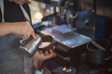 Barista in an apron making coffee in a coffee shop