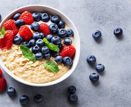 Bircher muesli or overnight oatmeal with apple, banana and blueberries in gray bowl, top view.