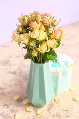 Vase with beautiful rose flowers and gift box on table