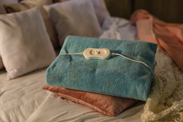 Electric heating pad with pillow on bed at night, closeup