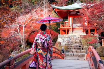 Japanese girl in Kimono dress smile in Daigoji temple with pond bridge pagoda and red maple garden...