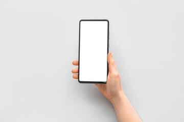 Female hand with modern mobile phone on light background, closeup