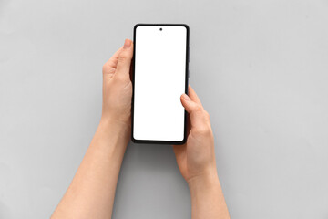 Female hands with modern mobile phone on light background, closeup