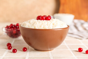 Bowl with delicious rice pudding and cranberry on tile table