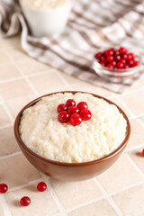 Bowl with delicious rice pudding and cranberry on tile table