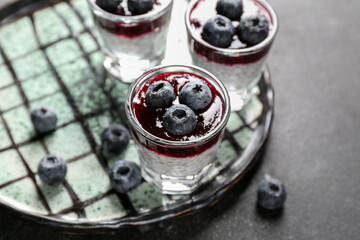 Plate with shots of delicious chia seed pudding and blueberry on black table